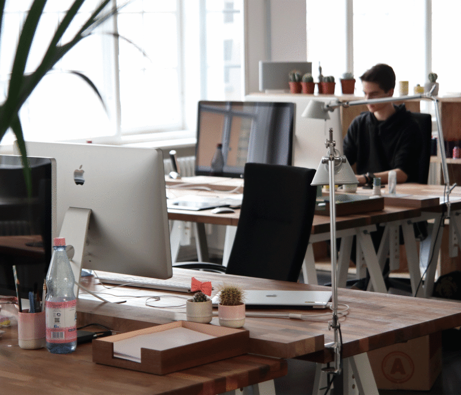 Modern office workspace with multiple iMac computers and employees focused on creative tasks.